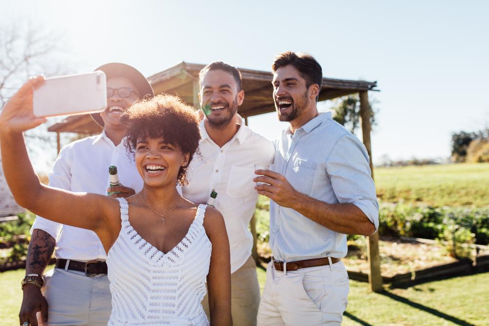 Group of mixed race people at a winery smiling taking a selfie