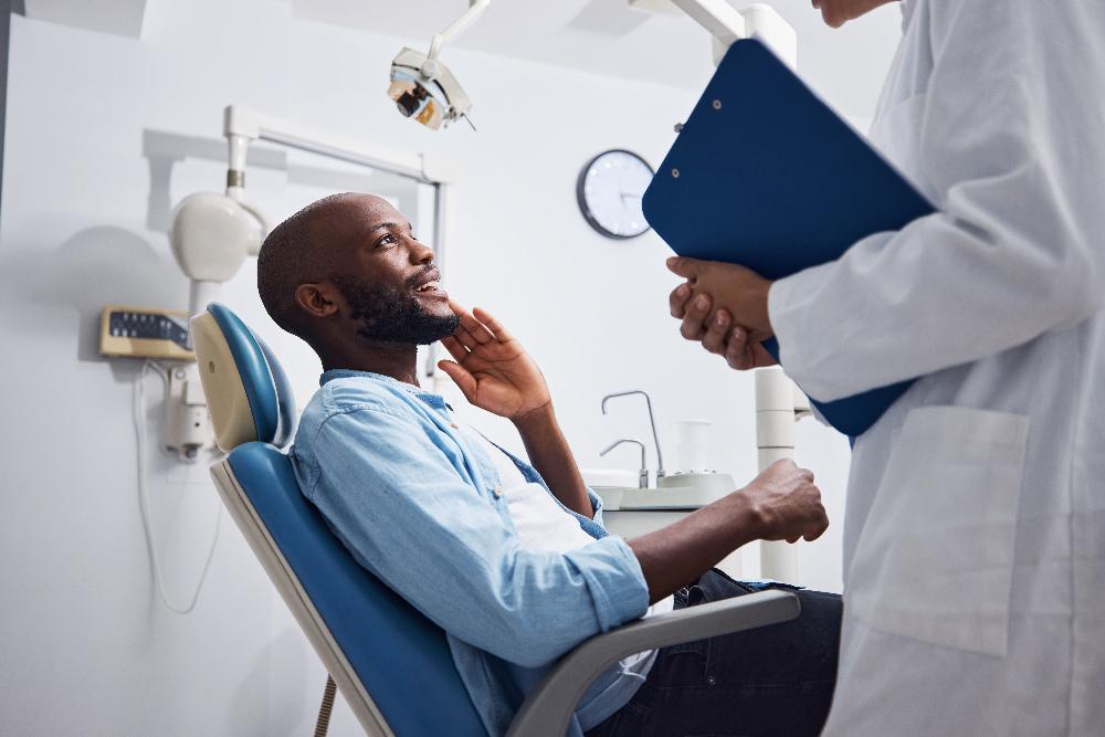 Black man holding his jaw and smiling at dentist, lindenhurst ny