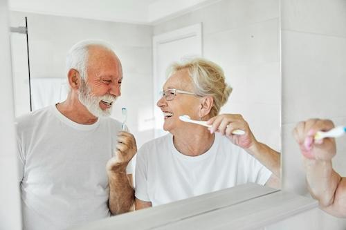 Older couple smiling at each other while brushing teeth, lindenhurst ny
