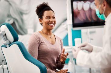 Woman sitting in dentist chair about talking to dentist, Lindenhurst NY