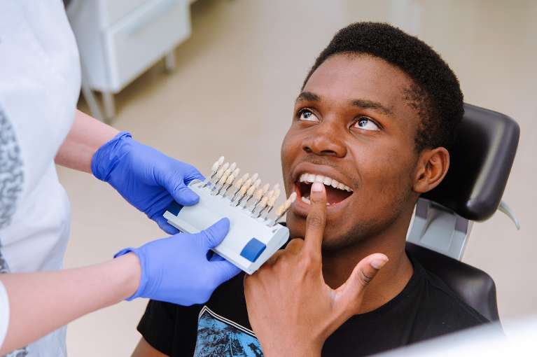 Black young man in dental chair touching his teeth before teeth whitening, lindenhurst ny
