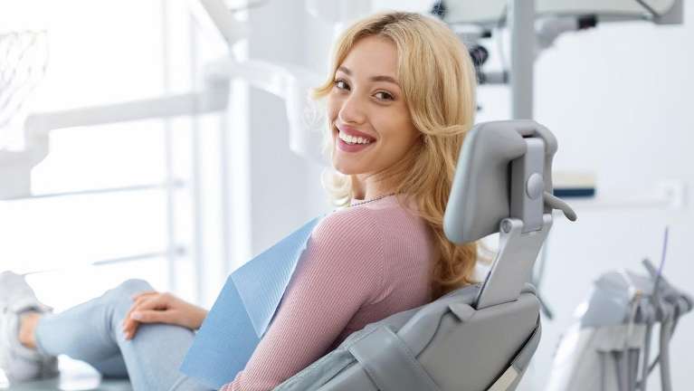 Young blonde woman sitting in dental chair smiling, lindenhurst ny