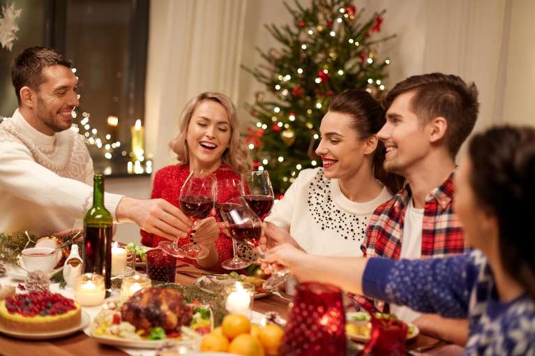 Friends smiling around a dinner table during the holidays, lindenhurst ny