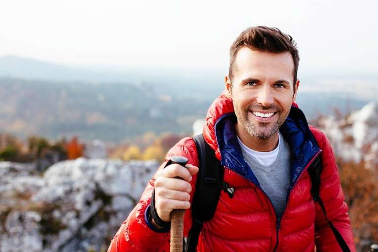 Man hiking outdoors with stick smiling, lindenhurst ny 