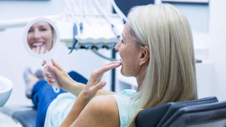 Older white woman in dental chair looking at dental implants, lindenhurst ny