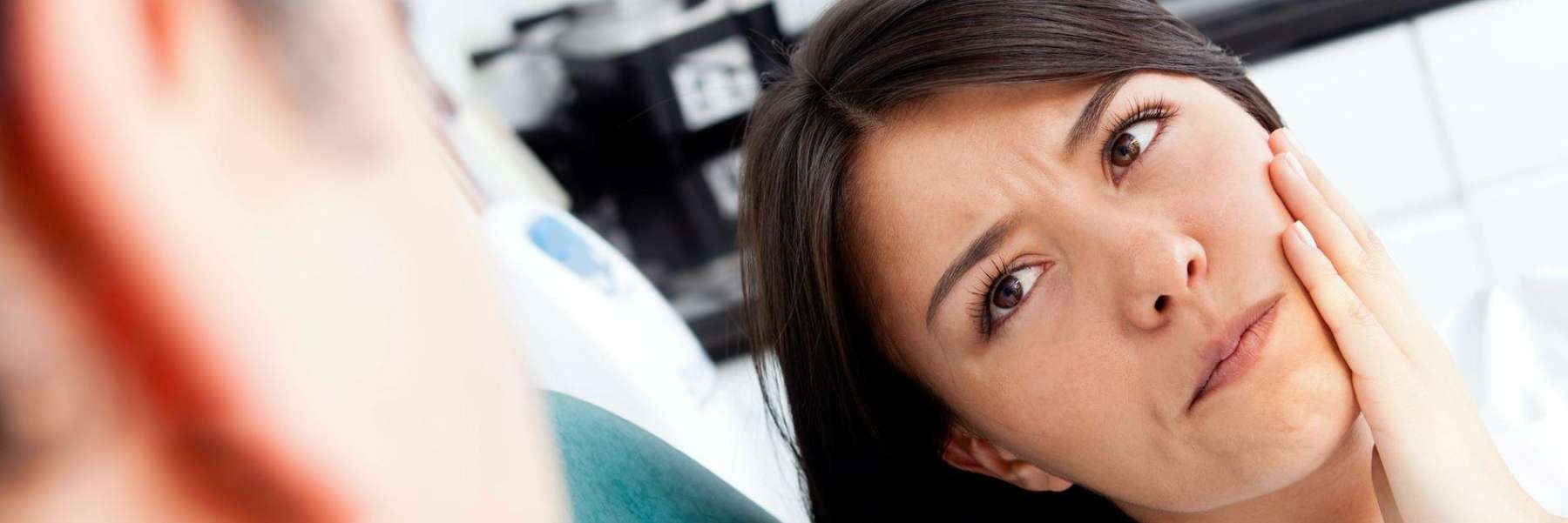 Woman holding jaw in need of emergency dentistry, Lindenhurst NY